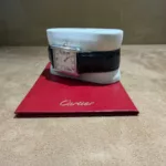 Vue de profil de la montre Cartier Tank Solo référence 2715, présentée avec ses papiers Cartier rouges.