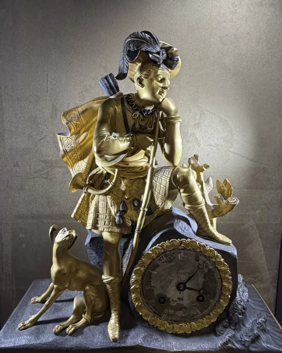 Pendule ancienne en métal doré à décor de personnage et chien, vue principale