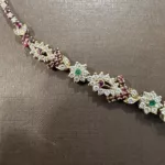 Détail des diamants et pierres rouges et vertes du collier en or jaune